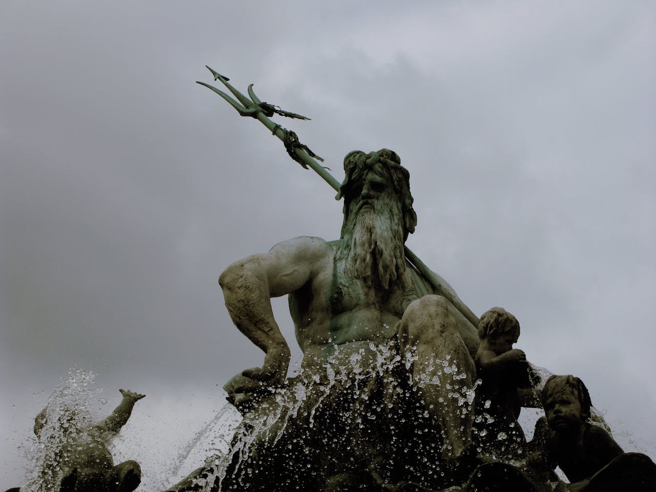 who-we-are Low-angle shot capturing a dramatic statue of Poseidon with dynamic water splashes.
